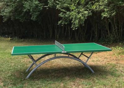 1 mesa de ping pong, modelo Economic Plus verde, instalada en un jardín.