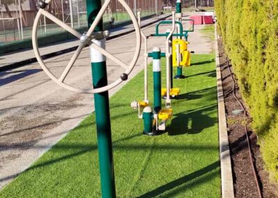 Outdoor fitness park with exercise equipment for arms and shoulders.