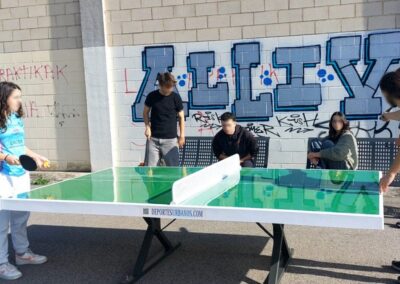 Jóvenes jugando al ping pong al aire libre en la mesa Forte de Deportes Urbanos